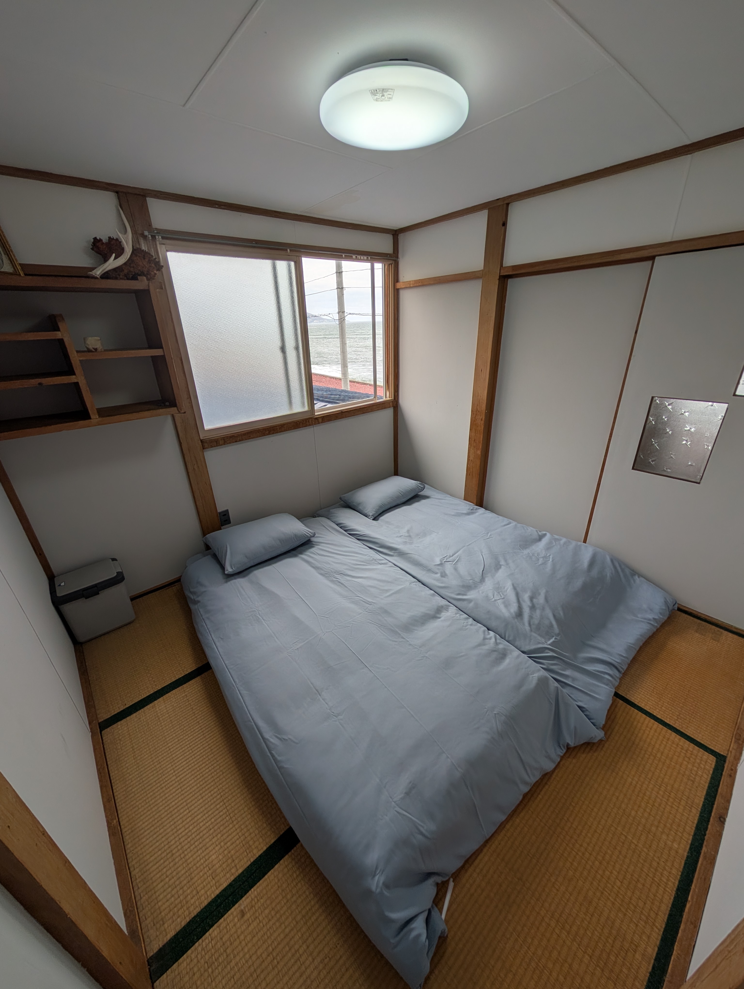 太平洋を望む窓と布団を備えた、コンパクトな畳の部屋。